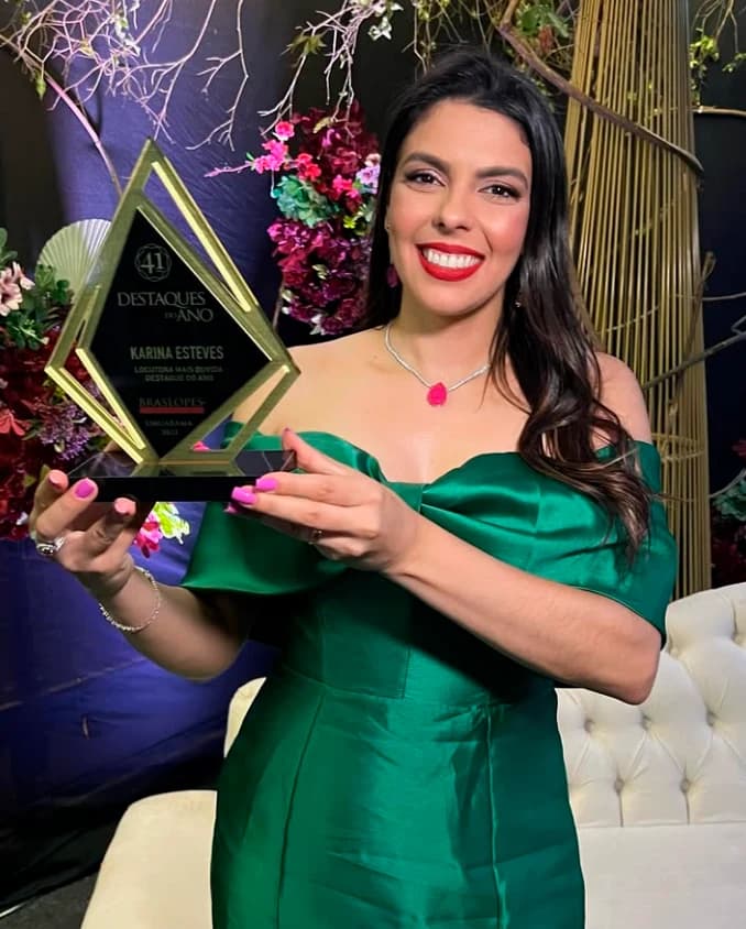 Karina Esteves segurando um prêmio durante evento de reconhecimento.